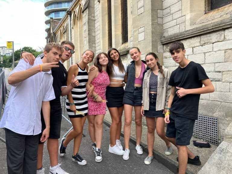 A group of international students smiling and posing together outside a historic stone building during a summer programme in Bournemouth, part of our English courses that combine language learning with cultural exploration and unforgettable experiences.
