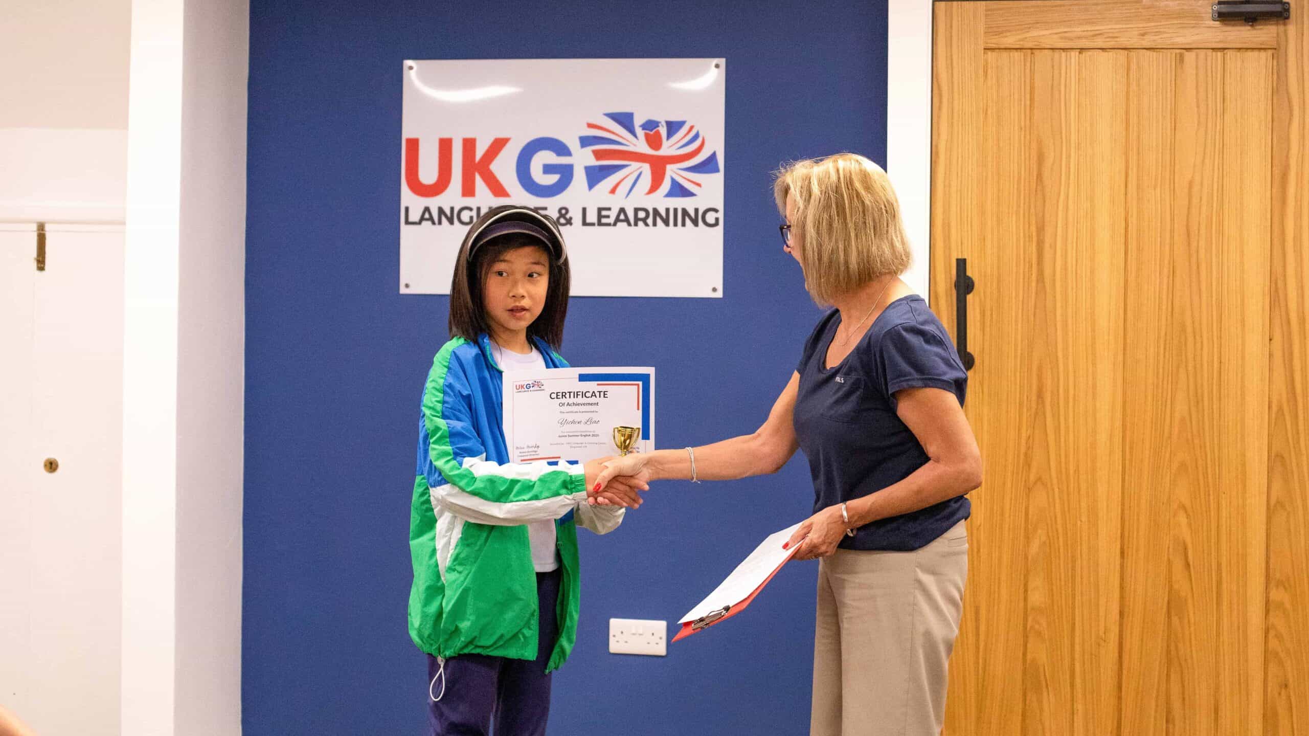 A student accepting her course certificate after completing her 2 weeks at our summer camp.